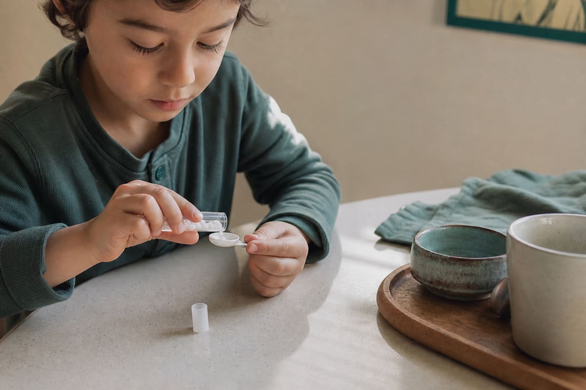 Petit tube de granules homéopathiques et cuillère doseuse sur une table de cuisine claire
