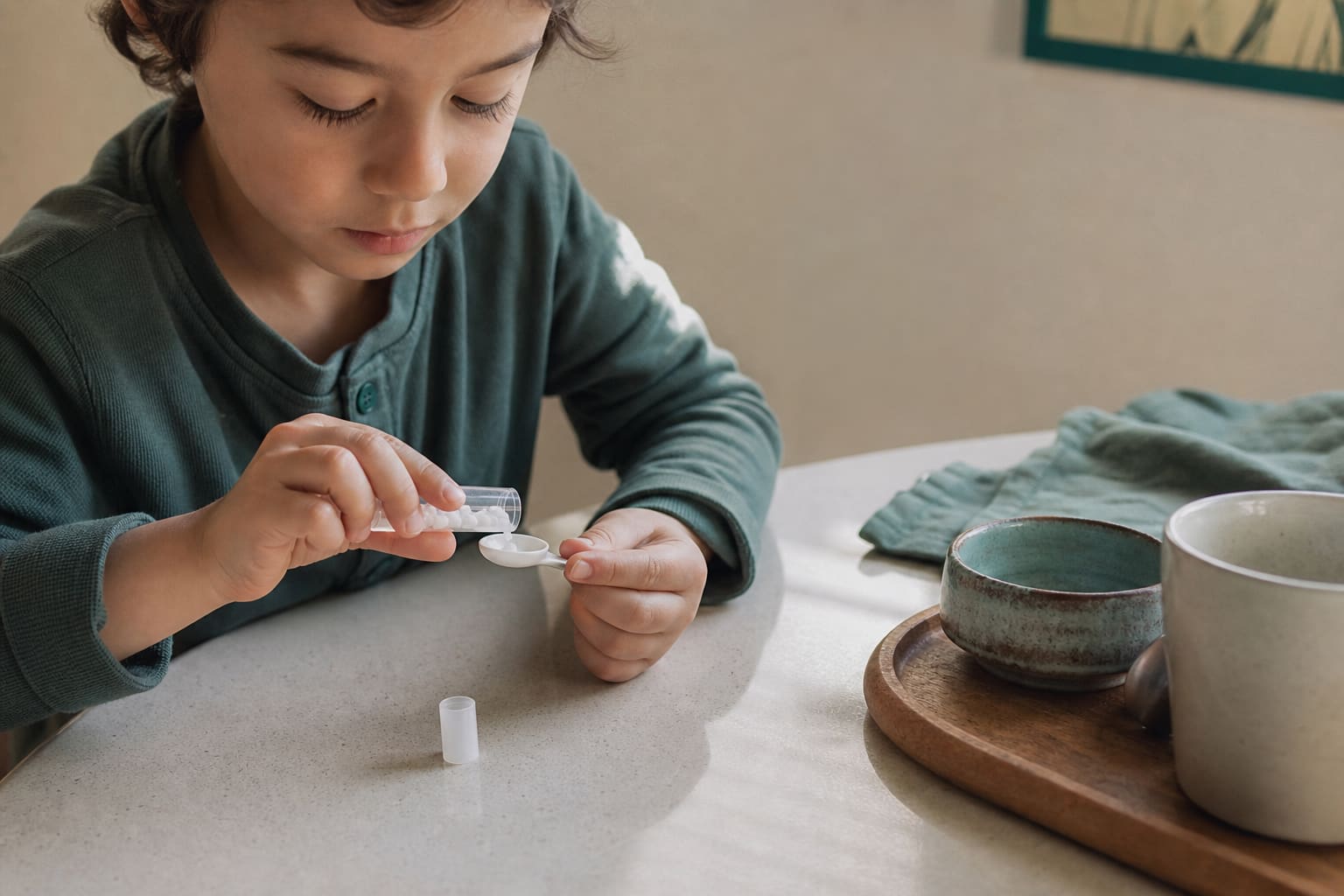 Petit tube de granules homéopathiques et cuillère doseuse sur une table de cuisine claire