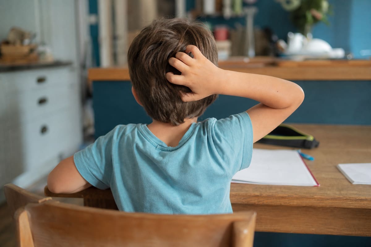 Enfant se grattant la nuque, zone typique des démangeaisons dues aux poux