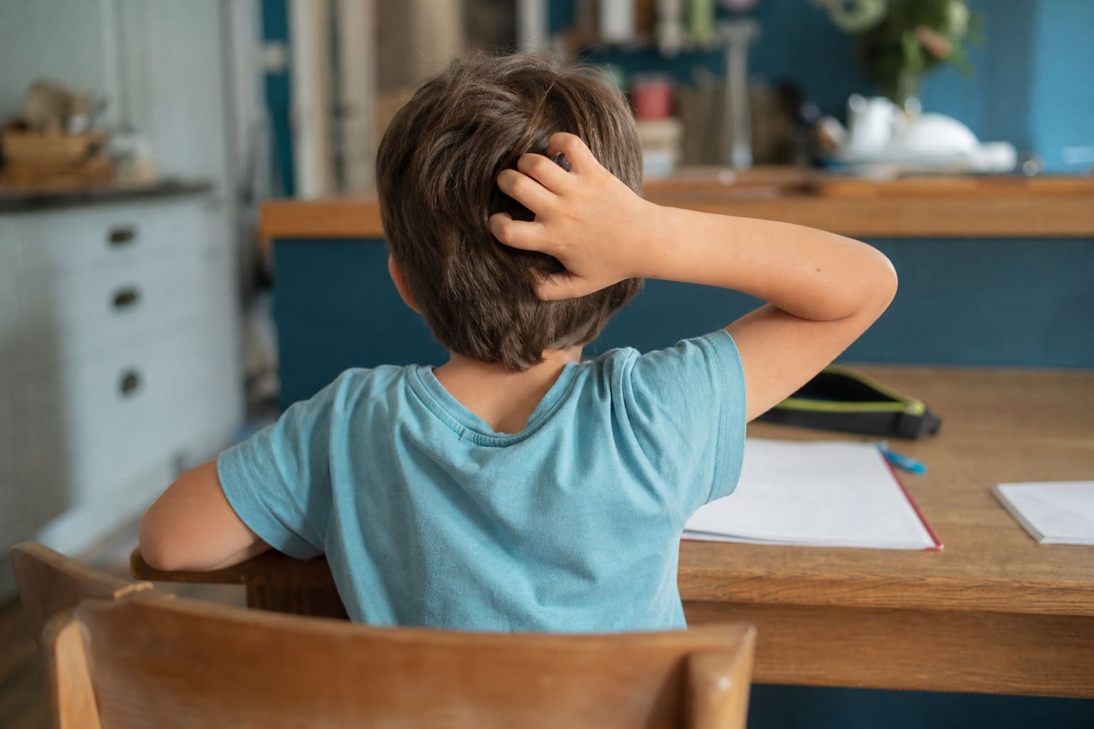 Enfant se grattant la nuque, zone typique des démangeaisons dues aux poux